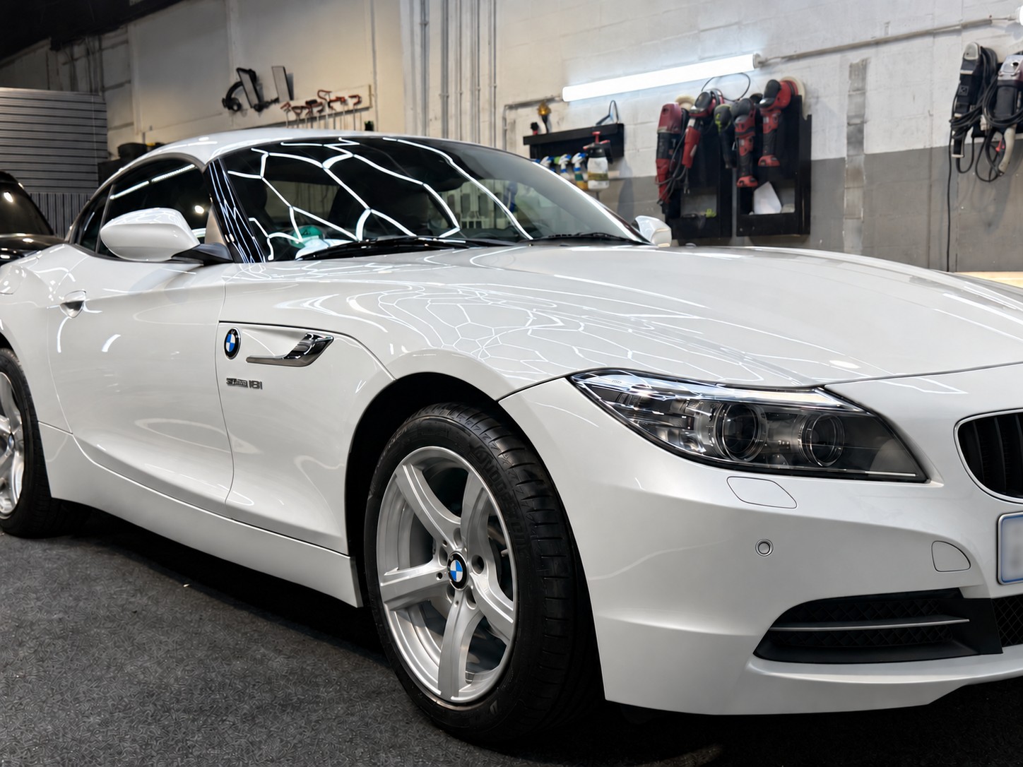Detailansicht des weißen BMW Z4 mit Lichtreflexionen. Lackglanz digital bearbeitet, Kennzeichen unkenntlich gemacht.