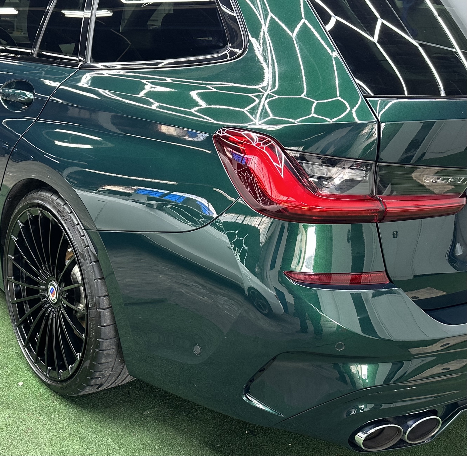 Grünes Fahrzeugheck mit Alpina-Rad und Spiegelungen im Lack