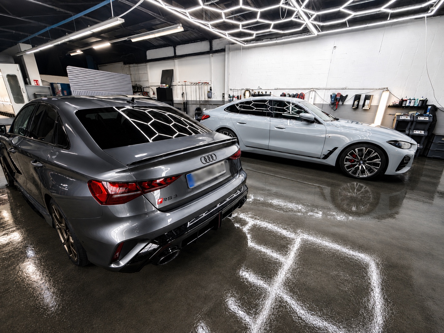 Grauer Audi RS 3 und weißer BMW unter der Hallenbeleuchtung