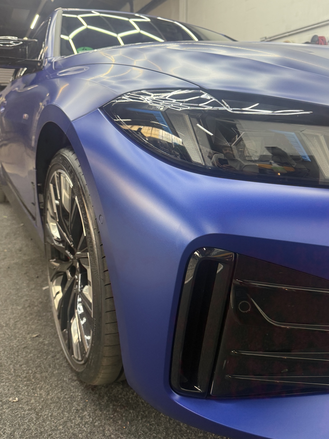 Mattblaue BMW-Front mit Scheinwerfer und Felge im Detail