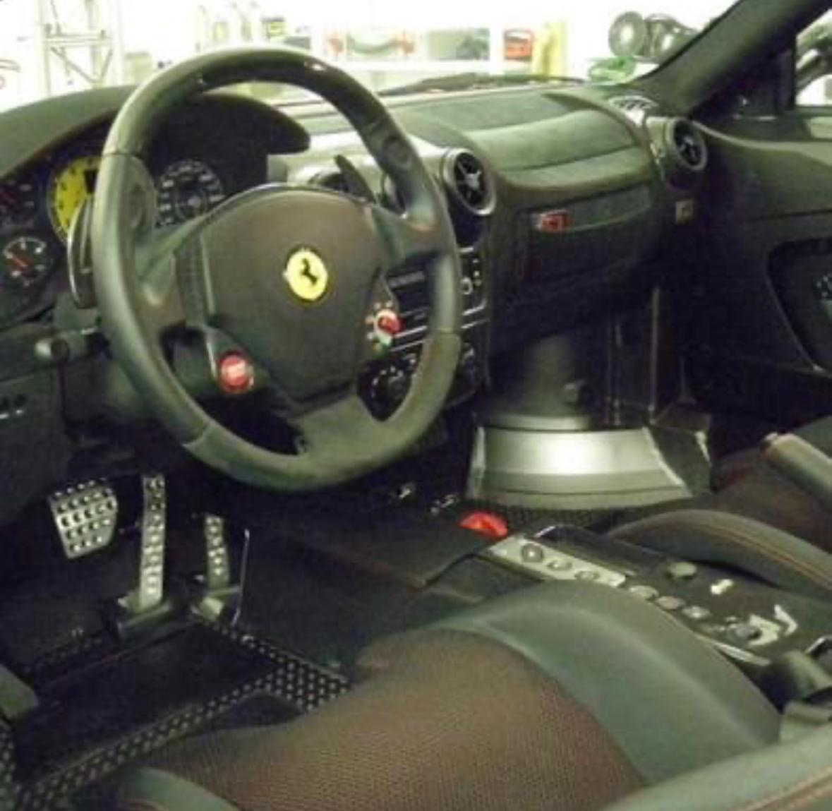 Dunkler Ferrari-Innenraum mit Lederlenkrad und Mittelkonsole