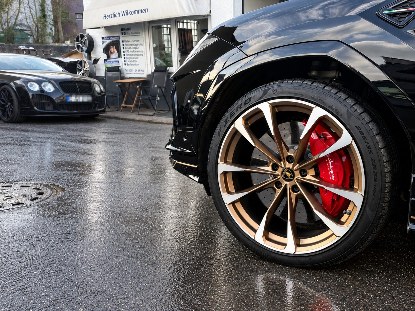 Lamborghini-Felge und Bentley vor Nano Car Cosmetic auf nassem Boden